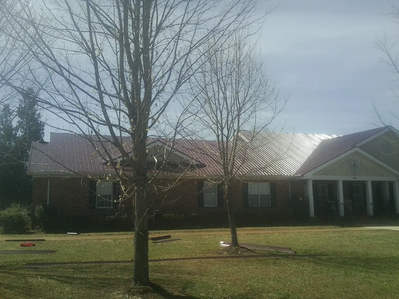 Red metal roof on a brick building seen from the front lawn in Westminster