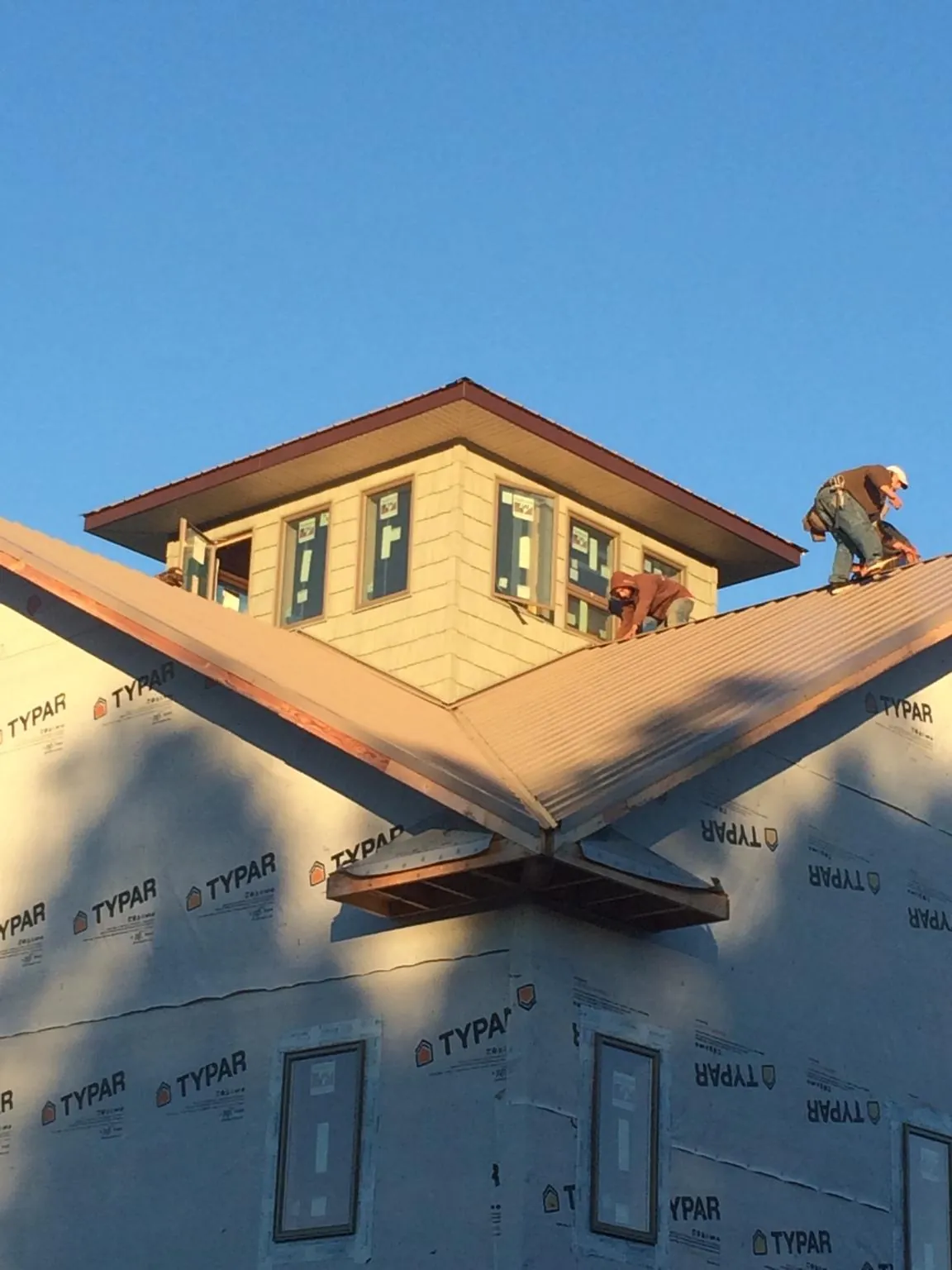 Roofers working around a rooftop cupola on a new metal roof at sunset — Roof Waterproofing in Westminster by Roofing Brothers